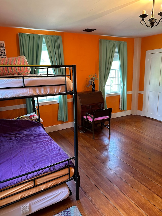 bedroom featuring a chandelier, hardwood / wood-style floors, and multiple windows