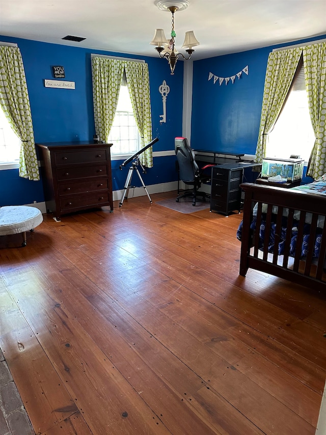 bedroom featuring a chandelier, hardwood / wood-style floors, and multiple windows