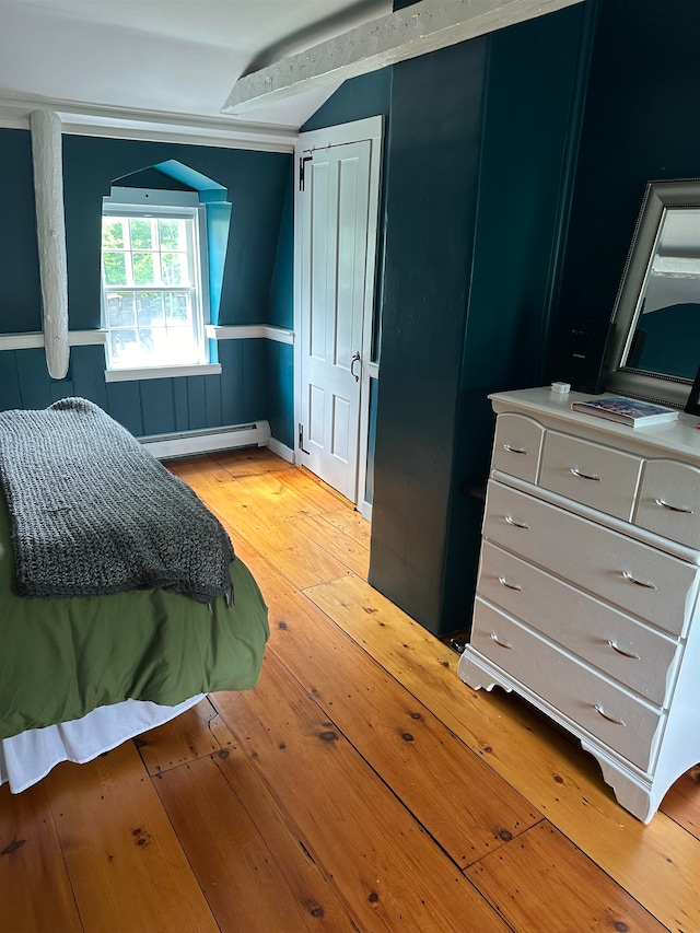 bedroom with light wood-type flooring, vaulted ceiling, and a baseboard radiator