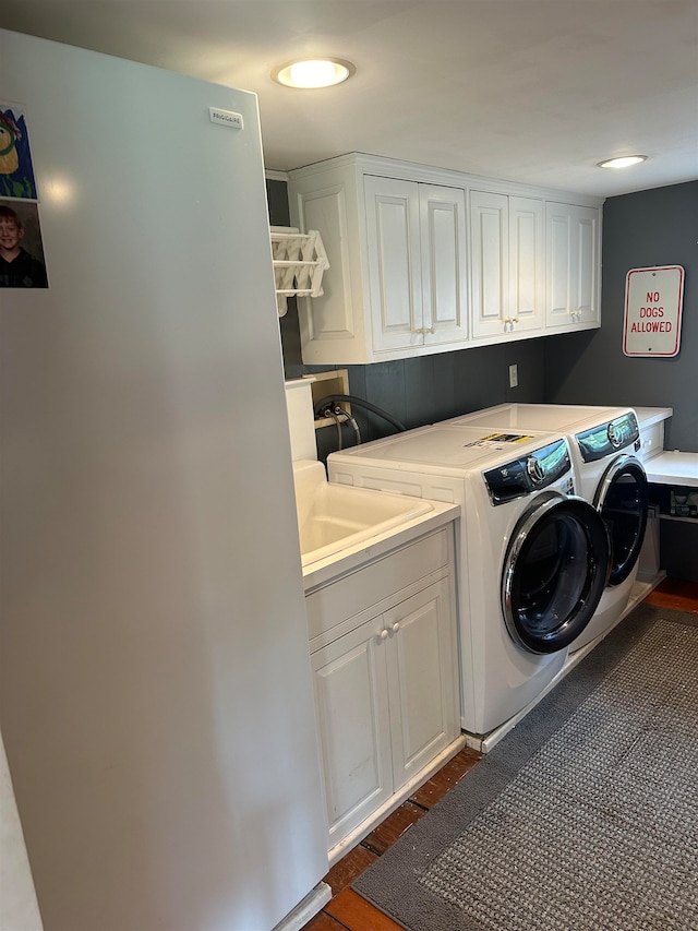 clothes washing area featuring cabinets, dark hardwood / wood-style flooring, and washing machine and clothes dryer