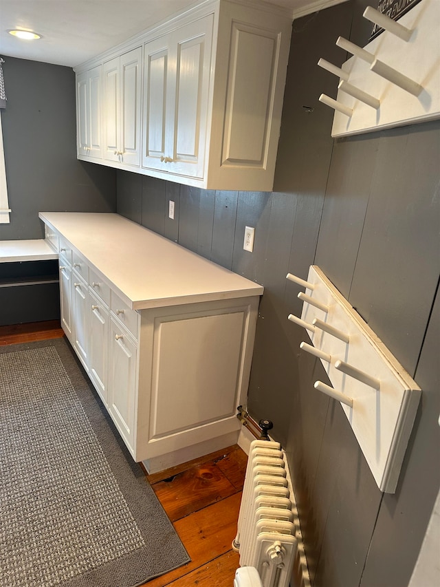 kitchen with radiator, dark wood-type flooring, and white cabinets