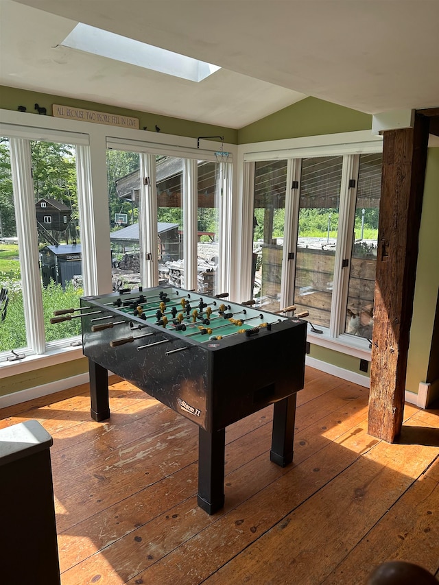 playroom with wood-type flooring, plenty of natural light, and vaulted ceiling with skylight