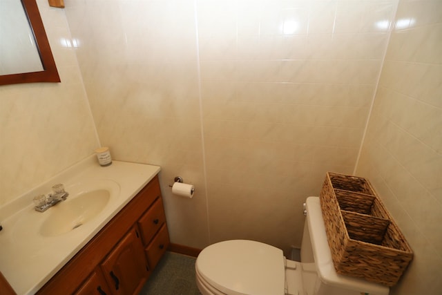 bathroom featuring vanity, tile walls, and toilet