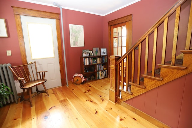 foyer with crown molding and light hardwood / wood-style floors