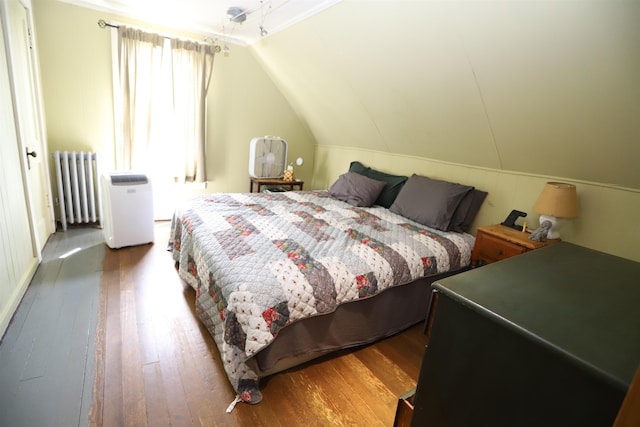 bedroom featuring lofted ceiling, radiator heating unit, and wood-type flooring