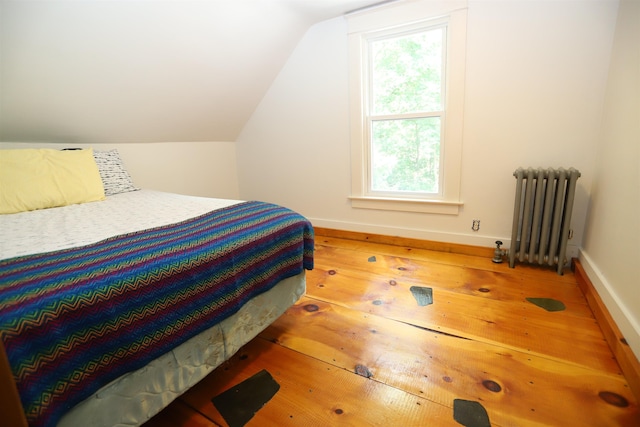 bedroom featuring wood-type flooring, lofted ceiling, and radiator heating unit