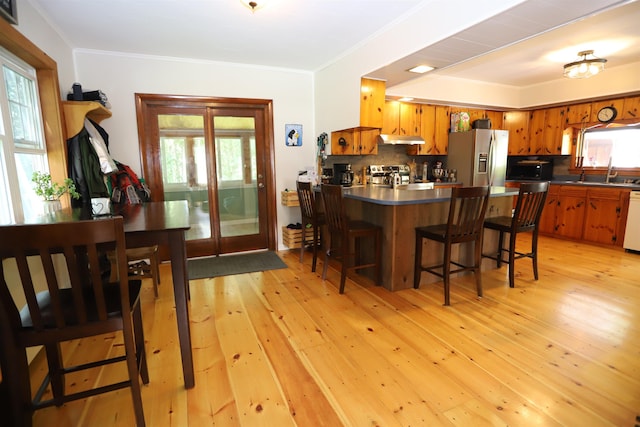 kitchen with a kitchen bar, backsplash, light hardwood / wood-style flooring, and appliances with stainless steel finishes