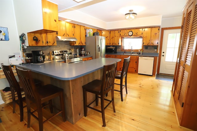 kitchen featuring sink, a kitchen breakfast bar, kitchen peninsula, stainless steel appliances, and backsplash