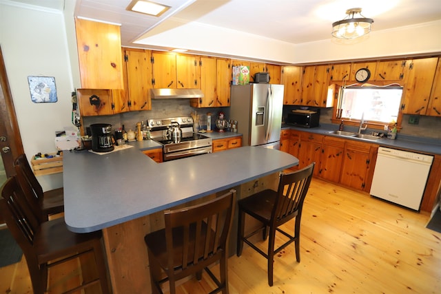 kitchen with sink, stainless steel appliances, kitchen peninsula, and a kitchen bar