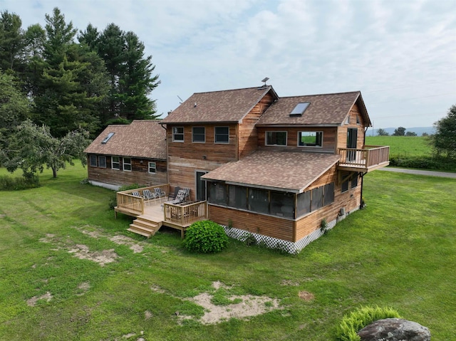 back of property with a wooden deck, a sunroom, and a lawn