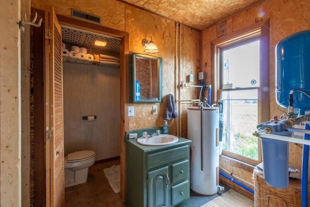 bathroom featuring vanity, electric water heater, toilet, and wood walls