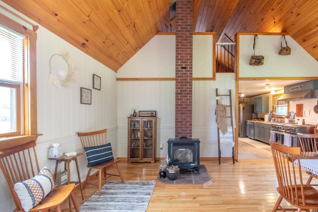 living area with wood ceiling, light hardwood / wood-style floors, a healthy amount of sunlight, and a wood stove