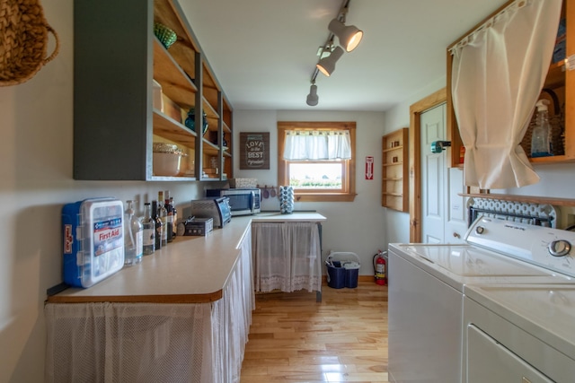 laundry area with washing machine and dryer, track lighting, and light hardwood / wood-style flooring