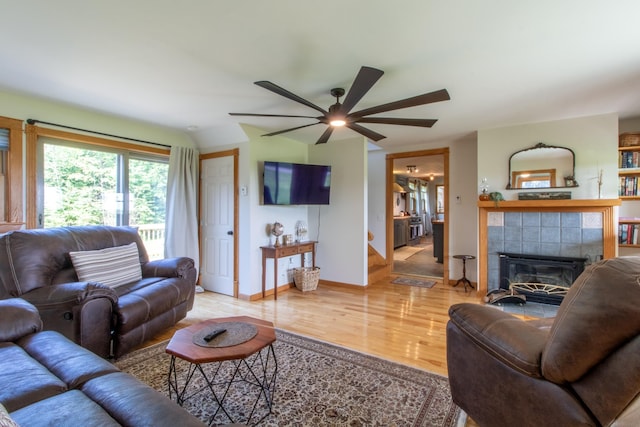 living room with a tiled fireplace, hardwood / wood-style floors, vaulted ceiling, and ceiling fan