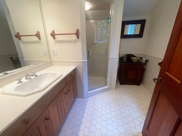 bathroom with a shower with door, vanity, and tile walls