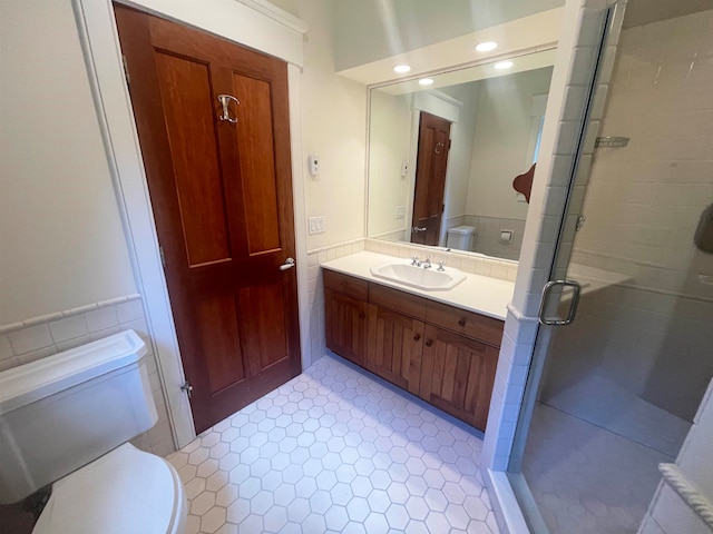 bathroom with an enclosed shower, vanity, toilet, and tile patterned flooring