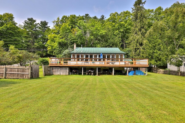 rear view of property with a wooden deck and a lawn