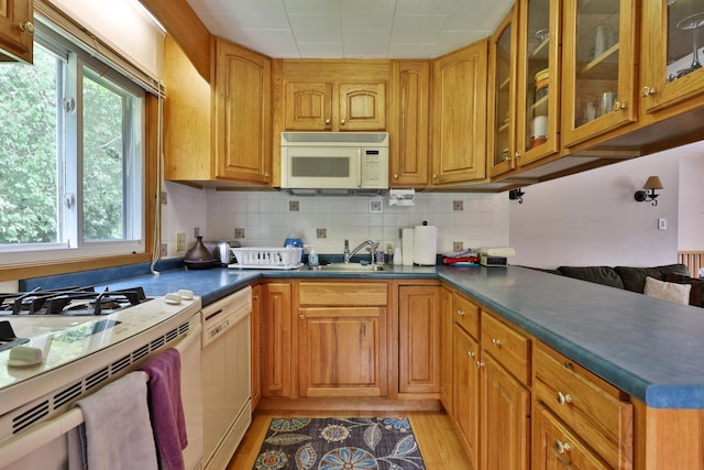 kitchen featuring tasteful backsplash, white appliances, light hardwood / wood-style floors, and sink