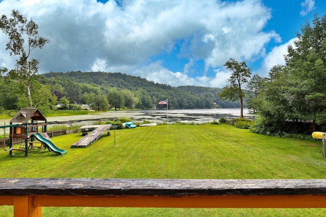 view of community with a playground, a water and mountain view, and a lawn