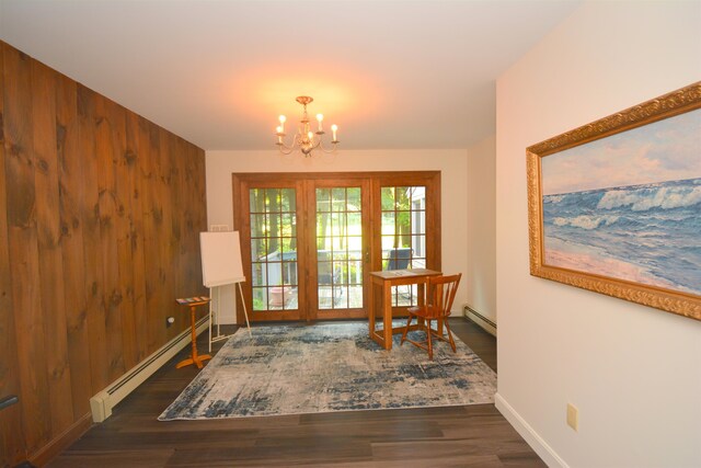 living area featuring an inviting chandelier, wooden walls, baseboard heating, and dark hardwood / wood-style flooring