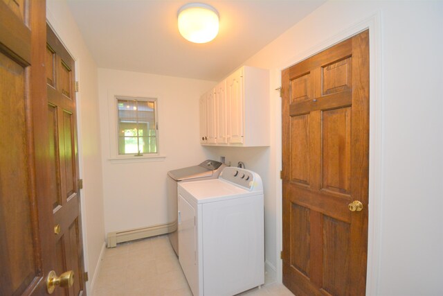 washroom with a baseboard heating unit, washer and dryer, and cabinets