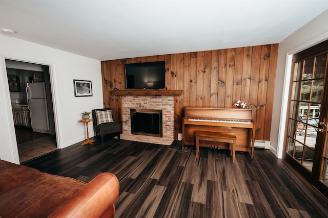 living room featuring a brick fireplace, wooden walls, baseboard heating, and dark hardwood / wood-style flooring