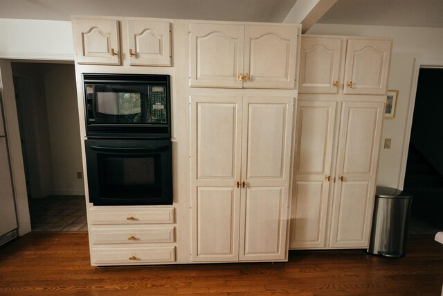 kitchen featuring cream cabinetry, dark hardwood / wood-style flooring, and black appliances