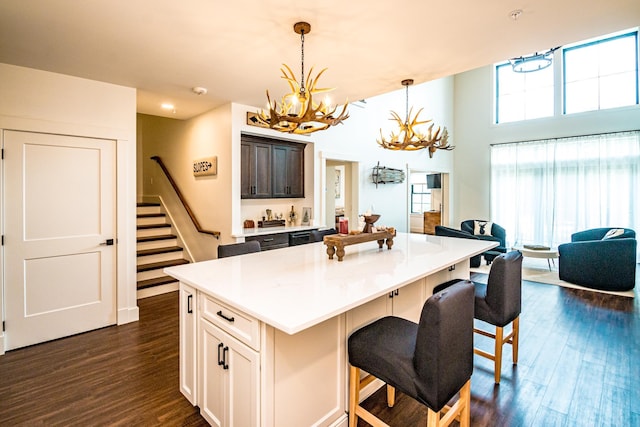 kitchen featuring dark wood-style floors, a kitchen island, a breakfast bar area, and an inviting chandelier