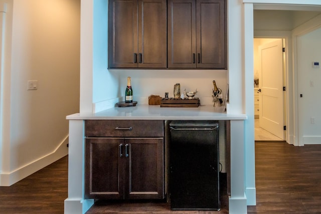 bar with a dry bar, dark wood-type flooring, and baseboards