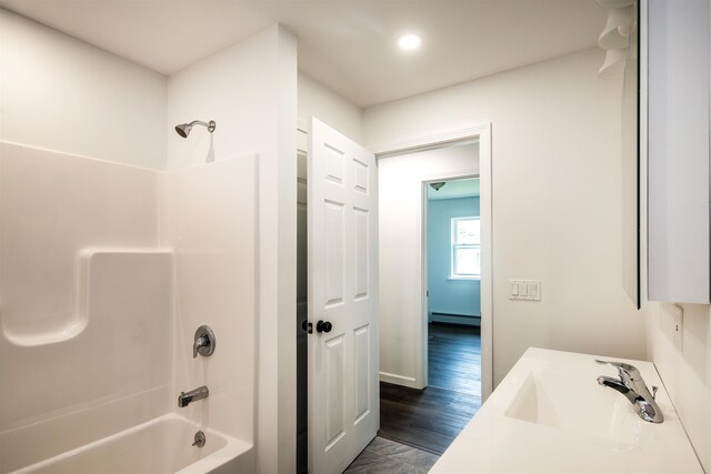 full bath featuring washtub / shower combination, baseboard heating, and vanity