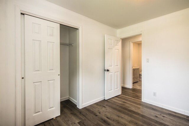 unfurnished bedroom with dark wood-style flooring, a closet, and baseboards