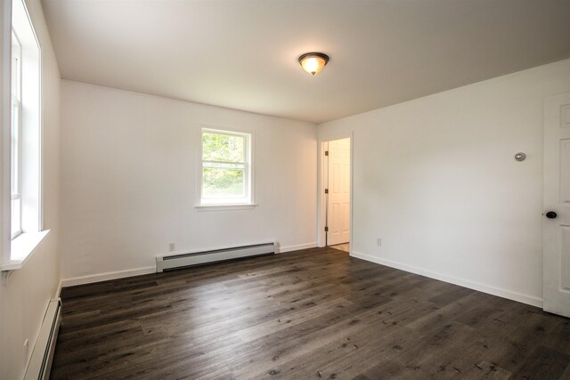 empty room featuring a baseboard heating unit, dark wood-style flooring, and baseboards