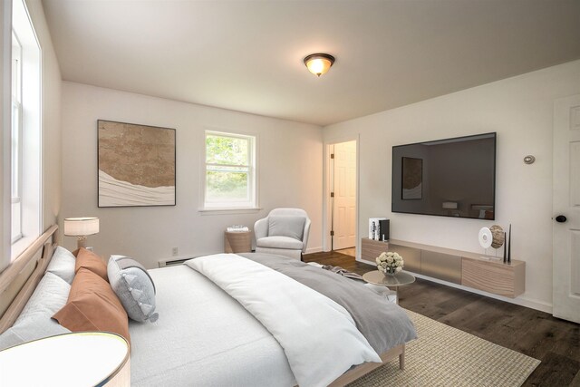 bedroom featuring a baseboard radiator, baseboards, and dark wood-style flooring