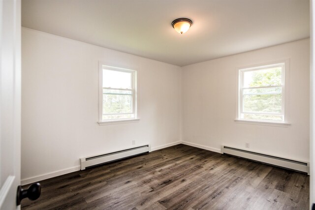 spare room featuring a baseboard heating unit, a baseboard radiator, a wealth of natural light, and dark wood-style flooring