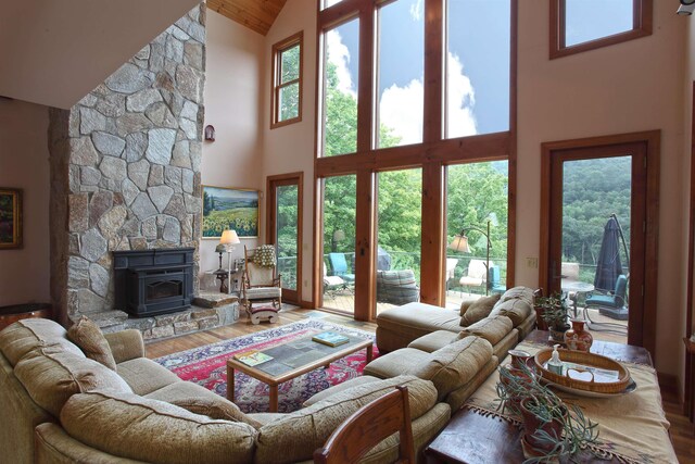 living room featuring a notable chandelier, light wood-type flooring, a high ceiling, and a wood stove