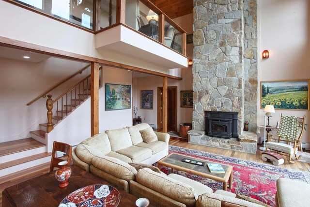 living room with a high ceiling, hardwood / wood-style flooring, a baseboard heating unit, and a notable chandelier