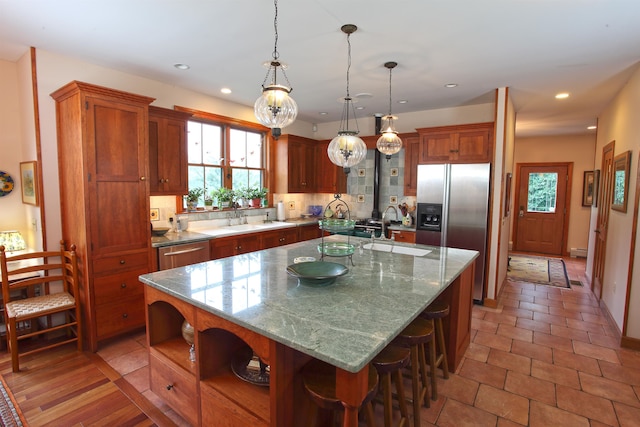 kitchen featuring hanging light fixtures, appliances with stainless steel finishes, sink, and a center island with sink