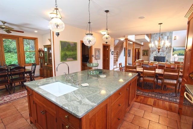 kitchen featuring ceiling fan, a kitchen island with sink, sink, and hanging light fixtures