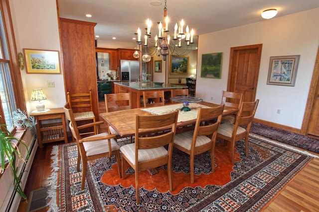 dining space featuring a baseboard heating unit, hardwood / wood-style floors, and an inviting chandelier