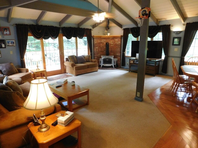 living room with a wood stove and vaulted ceiling with beams