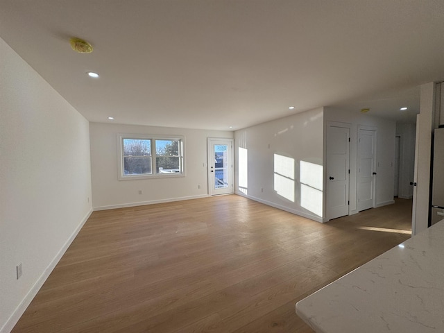 unfurnished living room featuring light wood finished floors, recessed lighting, and baseboards