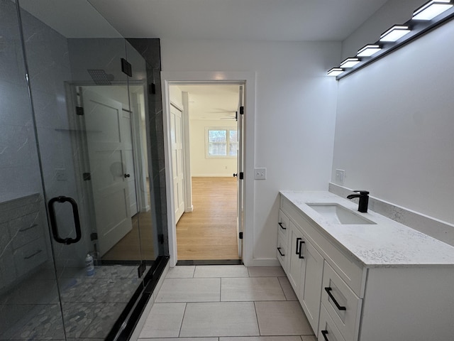 bathroom with baseboards, a shower stall, vanity, and tile patterned floors