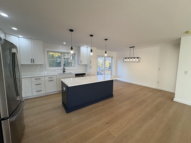 kitchen with tasteful backsplash, freestanding refrigerator, light wood-type flooring, and a sink