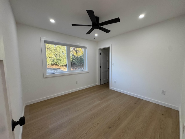 empty room with recessed lighting, wood finished floors, a ceiling fan, and baseboards