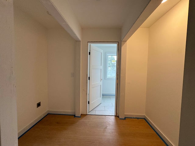 corridor with baseboards and wood finished floors