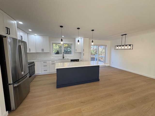 kitchen featuring backsplash, light wood-style flooring, stainless steel appliances, and a sink