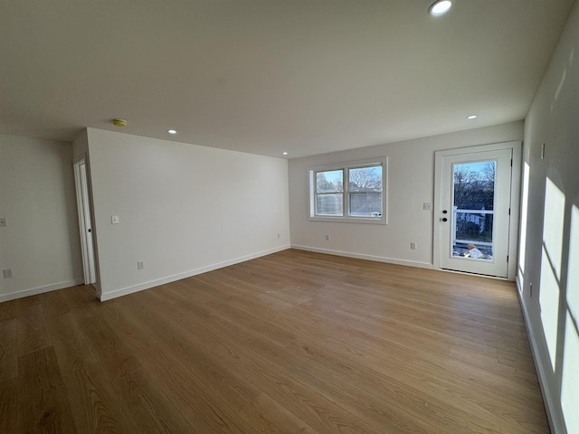 unfurnished living room featuring recessed lighting, light wood-style flooring, and baseboards