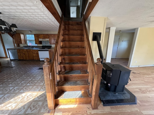 stairway featuring baseboards, a textured ceiling, wood finished floors, and a wood stove