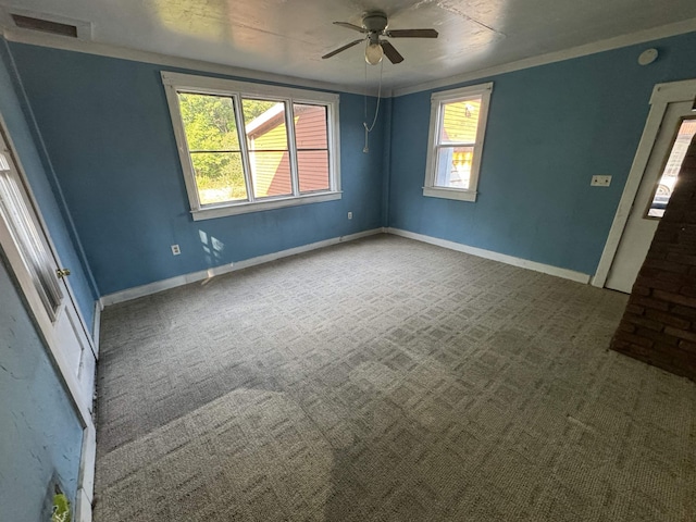 carpeted empty room featuring visible vents, a ceiling fan, baseboards, and ornamental molding