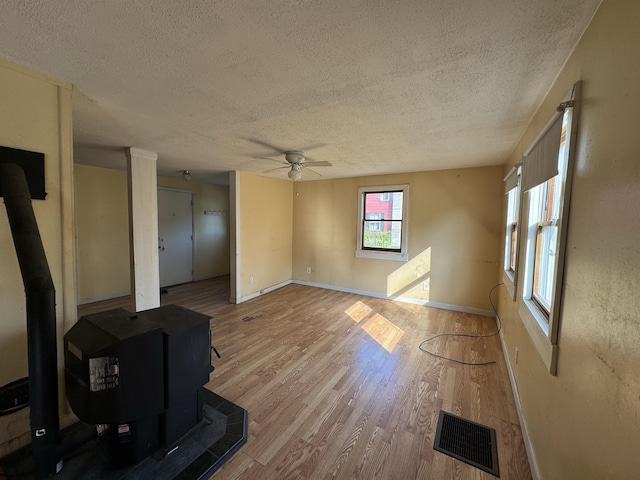 living area featuring visible vents, a textured ceiling, a wood stove, and wood finished floors